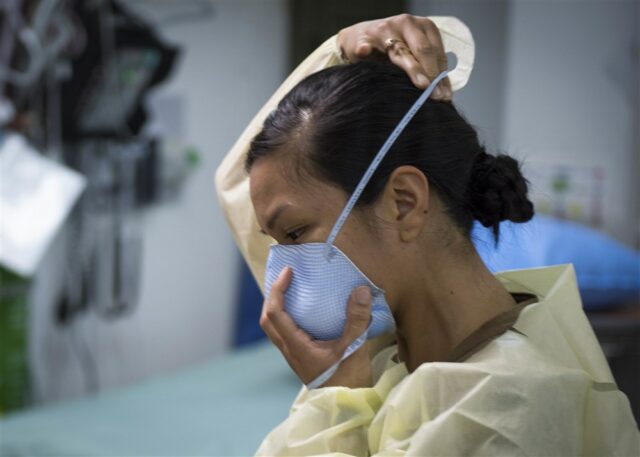 Female medical professional in emergency gear donning mask